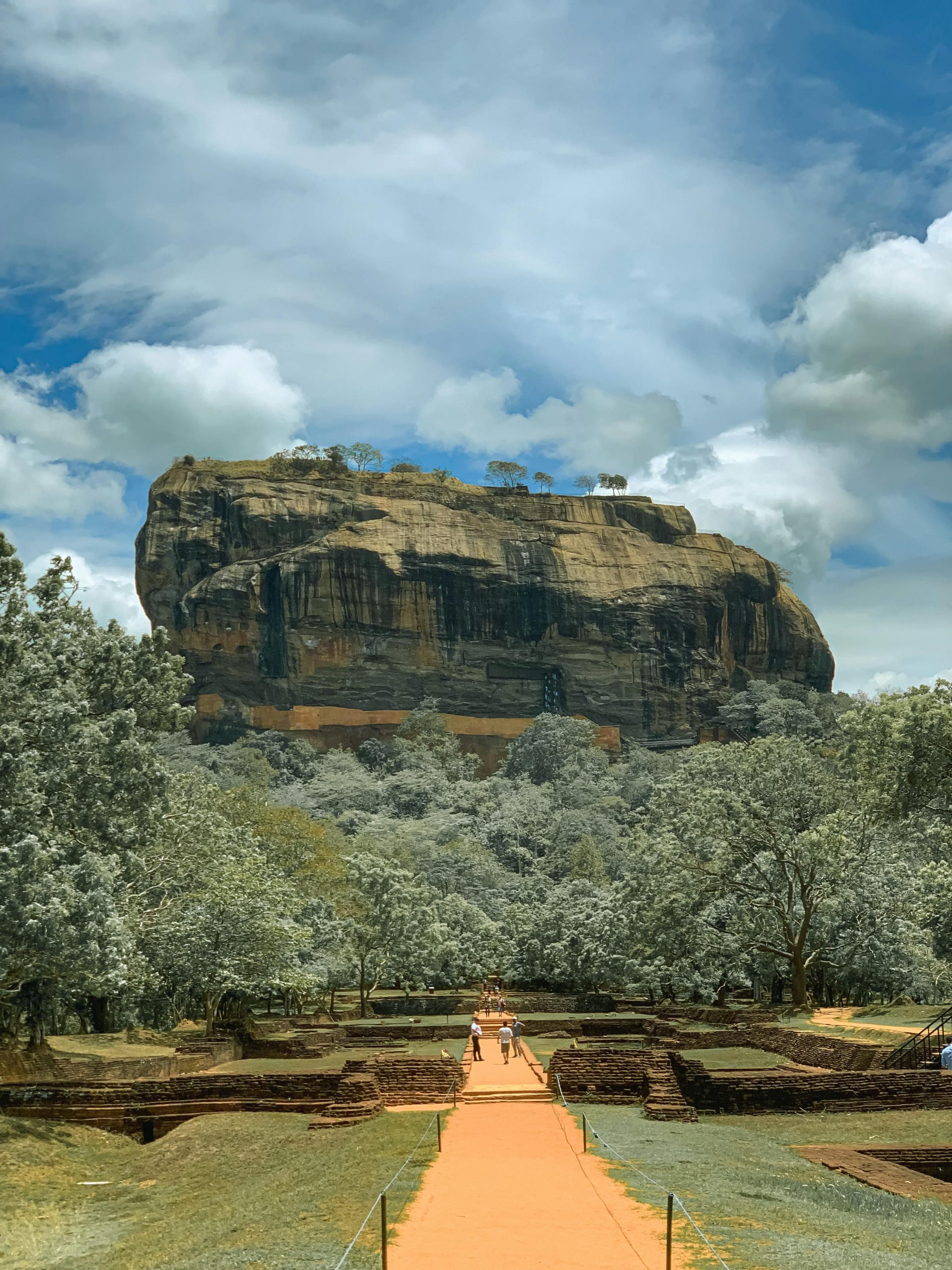 Breathtaking view of Sigiriya Rock Fortress surrounded by lush greenery on a sunny day.